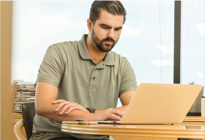 hombre con barba mirando su computadora portátil en una oficina