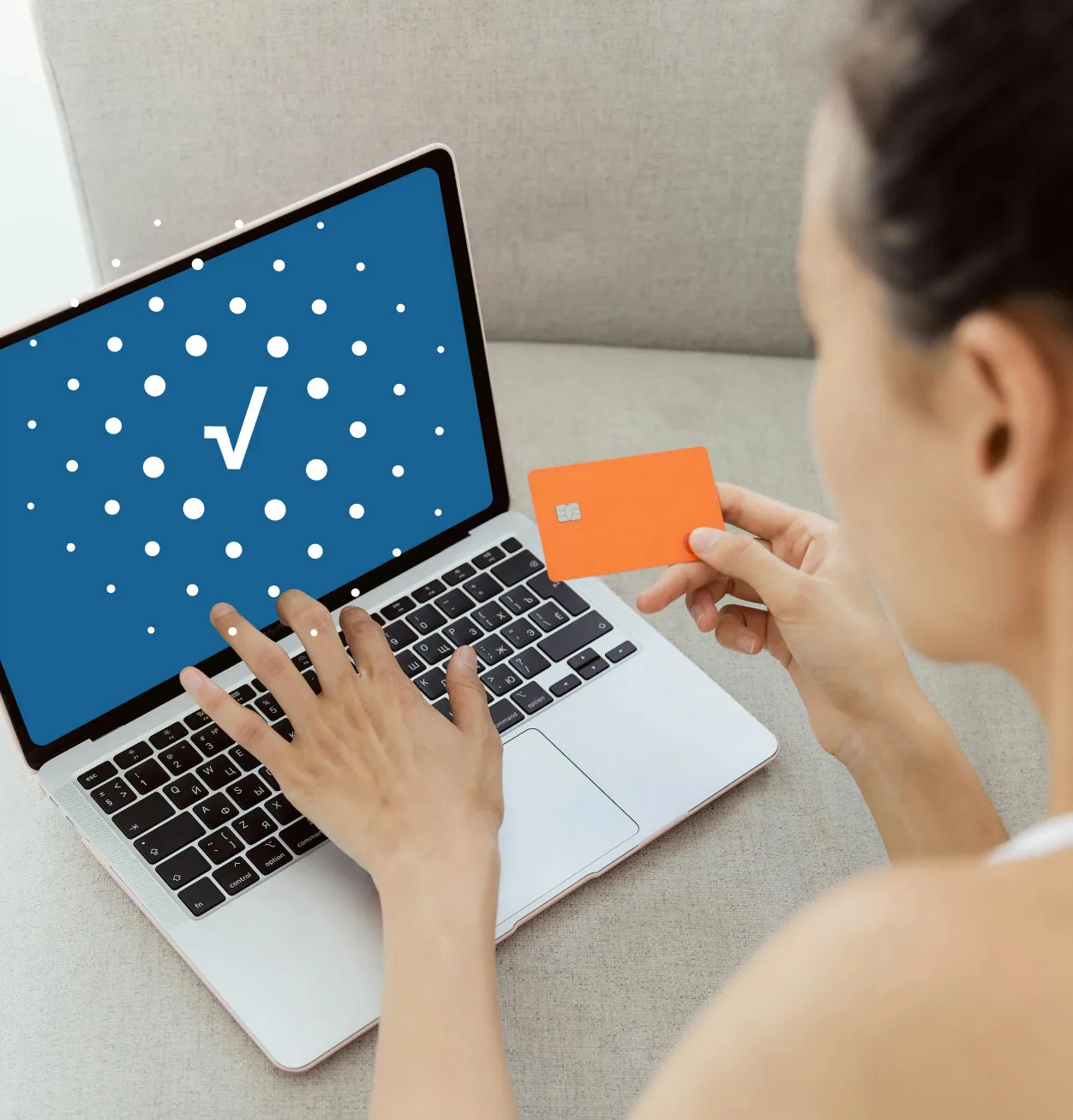 una mujer con su computadora portátil y su tarjeta de crédito en mano, la pantalla de su computadora muestra un icono de aprobado